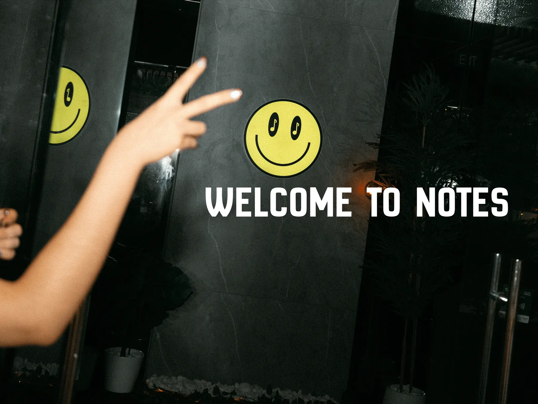 Welcome to Notes — a guest waving in front of the cafe signage